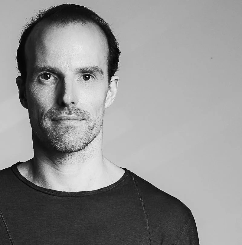 Tobias Wagner facing the camera against a plain wall, black and white